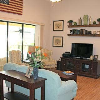A cozy living room featuring a sofa, television, bookshelf, and decor with a wooden floor and a patio door.