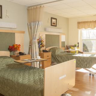 A well-lit hospital room with two patient beds separated by a privacy curtain.