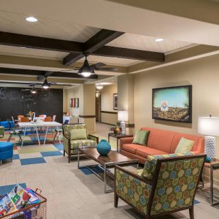 A modern indoor lounge area with comfortable seating and a play space for children.