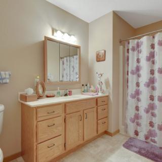 A well-organized bathroom with a wooden vanity, mirror, and floral shower curtain.