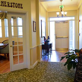 A well-lit hallway with doors, furniture, and decorative plants.