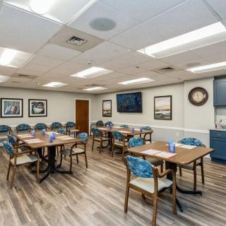 A well-lit dining area with multiple tables and chairs, decorated with framed pictures on the walls.