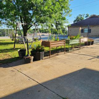 A sunny outdoor space featuring organized planters and a lush tree, perfect for gardening enthusiasts.
