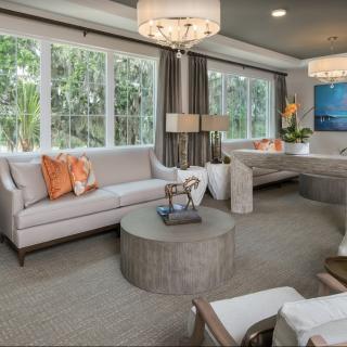 A modern living room with large windows, stylish sofas, a round coffee table, and decorative lighting.