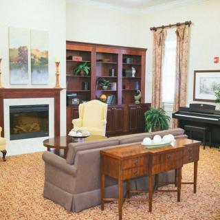 A cozy living room featuring a fireplace, bookshelves, and a piano.