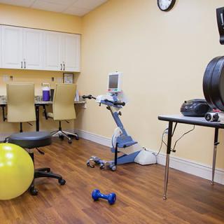 A rehabilitation room equipped with a therapy ball, dumbbell, and various medical devices.