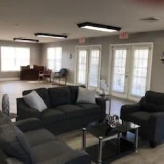 A modern living room with dark sofas and bright windows.