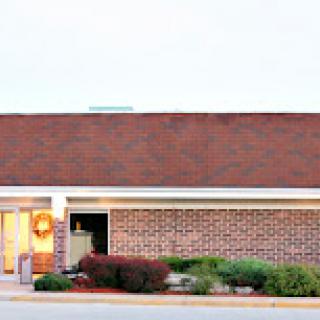 A brick building featuring a tiled roof and well-maintained landscaping.