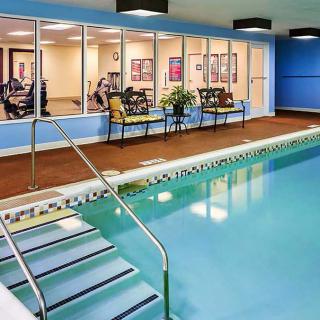 Indoor swimming pool adjacent to a fitness center with exercise equipment.