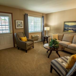 A cozy living room interior with a sofa, armchairs, and a coffee table arranged neatly.