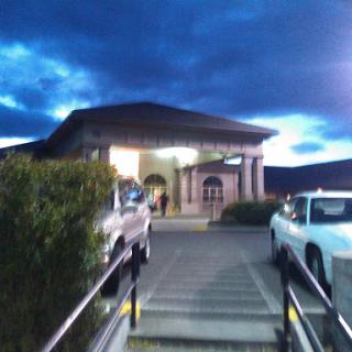 An evening view of a building with a welcoming entrance and cloudy skies above.