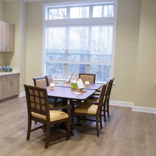 A cozy dining room with a wooden table and chairs, set by a large window.
