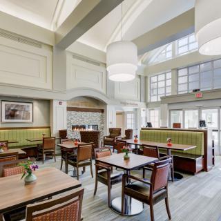 A modern restaurant interior featuring elegant tables, comfortable seating, and large windows for natural lighting.