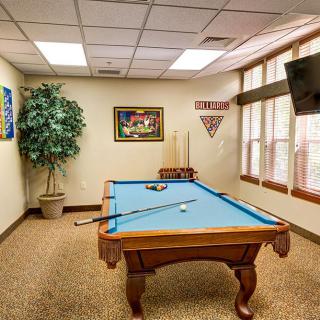 A cozy game room featuring a pool table, wall art, and a television.