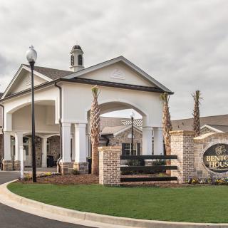 A modern residential building entrance with arches and manicured landscaping.