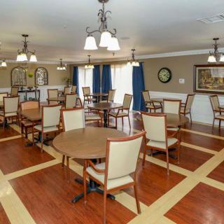 A spacious dining area with neatly arranged tables and chairs, featuring elegant lighting and a wooden floor.