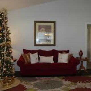 A cozy living room with a red sofa, decorated Christmas tree, and framed artwork on the wall.
