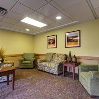 A comfortable waiting room with a sofa and chairs, decorated with paintings on the walls.