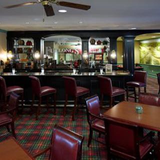A cosy bar and restaurant interior with red leather seating and wooden tables.