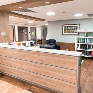 A modern reception area in a healthcare facility, featuring a wooden desk and comfortable seating.