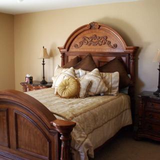 A traditional style bedroom featuring a wooden bed with decorative pillows and matching nightstands.