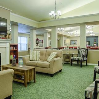 A cozy living room with comfortable sofas, a coffee table, and a television, featuring elegant chandeliers and soft carpeting.