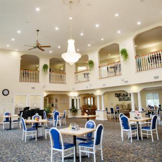 A spacious and elegantly designed dining area featuring blue chairs and a beautiful chandelier, perfect for gatherings.