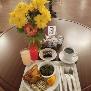A neatly arranged breakfast table with a colorful flower vase and various dishes.