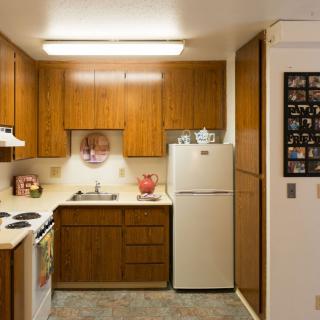 A cozy kitchen with wood cabinets, a refrigerator, sink, and stove.