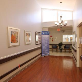 A well-lit hallway with artwork on the walls and wooden flooring.