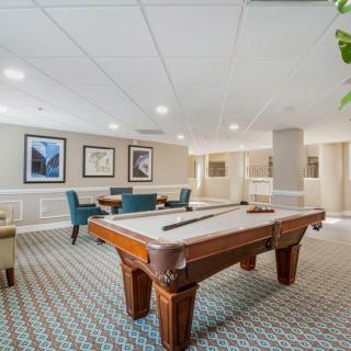 A recreation room featuring a pool table and seating area with artwork on the walls.