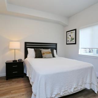 A minimalist bedroom with a neatly made bed, a nightstand with a lamp, and simple decor.
