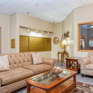 A cozy living room with a beige sofa, armchair, and a wooden coffee table adorned with decorative items.