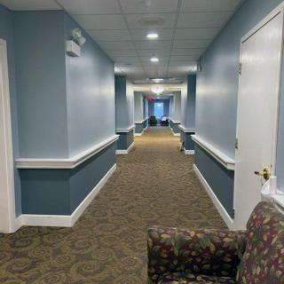 A long corridor with blue walls, carpeted flooring, and overhead lighting.