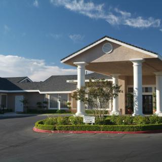 A modern residential building entrance with columns and landscaped surroundings.