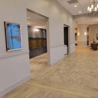 A modern hallway with wood flooring and elegant chandeliers.