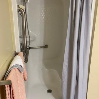 A bathroom with a shower, featuring a curtain and towels.