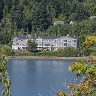 Scenic view of a building by the lake surrounded by lush greenery.