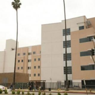 A multi-story hospital building with palm trees in front.