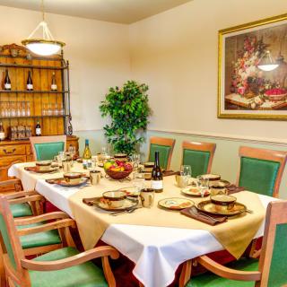 Elegantly set dining room table with green chairs and artful decor.