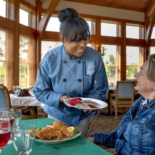 A chef serving food to a customer in a restaurant setting, showcasing hospitality and service.