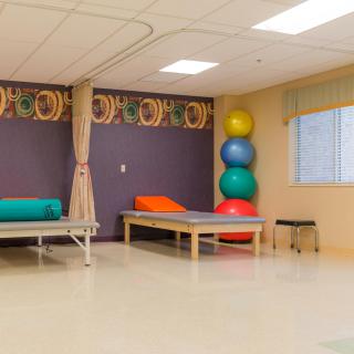 A therapy room equipped with treatment beds and stacked exercise balls.
