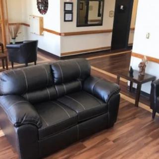 A cozy living room setup featuring a black leather sofa, wooden flooring, and complementary furniture.