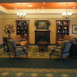 A cozy living room with a fireplace, surrounded by comfortable seating and decorated bookshelves.