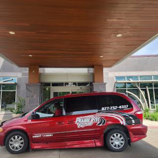 A red minivan with advertisement graphics parked in front of a modern building.