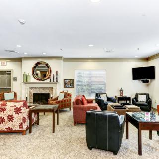 A cozy living room with various seating options, a fireplace, and a mounted television.