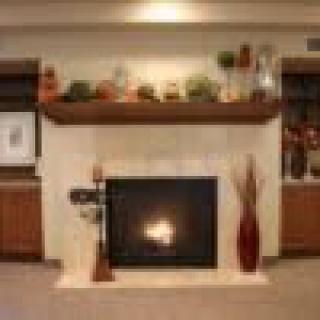 A cozy living room with a lit fireplace, adorned mantel, and decorative shelves.