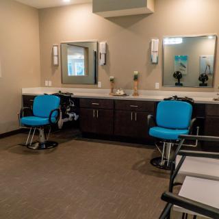 Modern barbershop interior with blue chairs and mirrors.