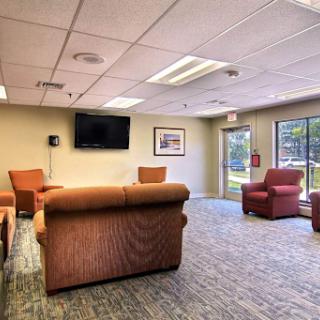 A comfortable waiting room featuring modern furniture and a television.