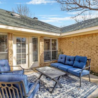 A cozy patio area with blue outdoor furniture and a patterned rug against a brick house.